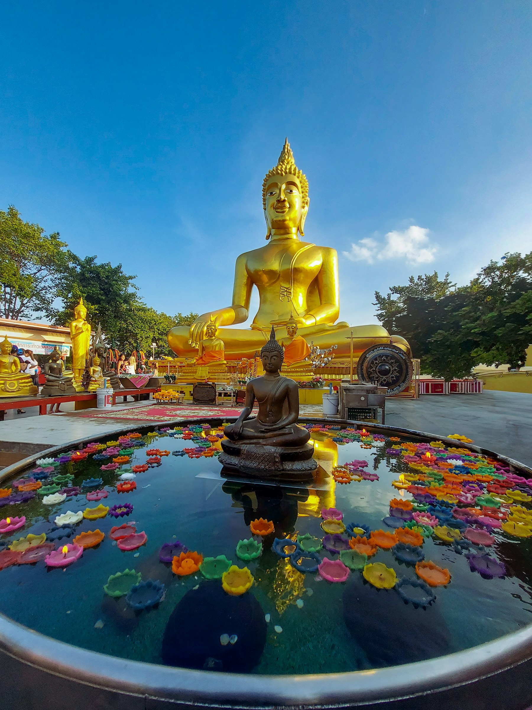 Golden Buddha statue surrounded by colourful floating candles