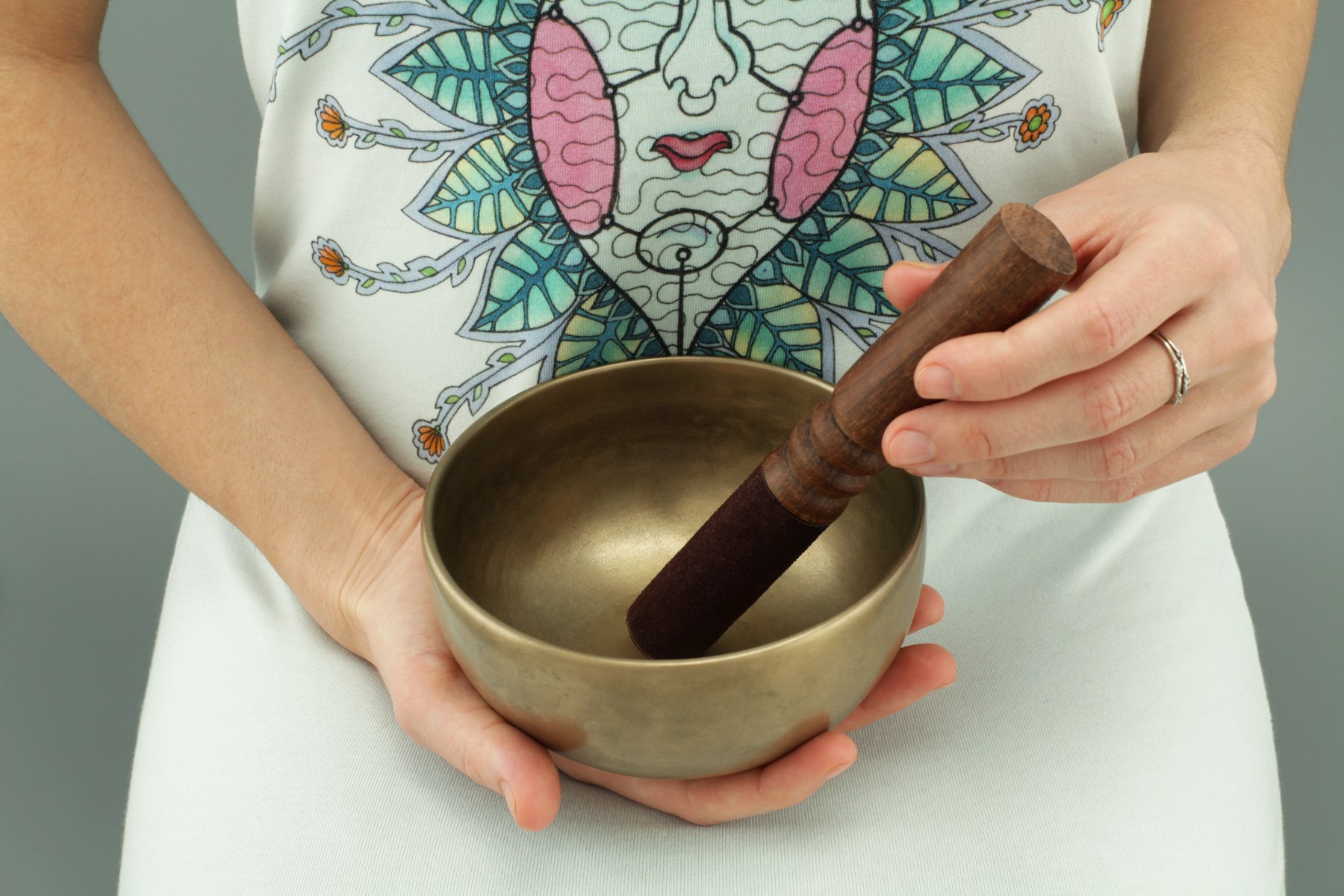 Hands playing a Tibetan singing bowl used in sound healing